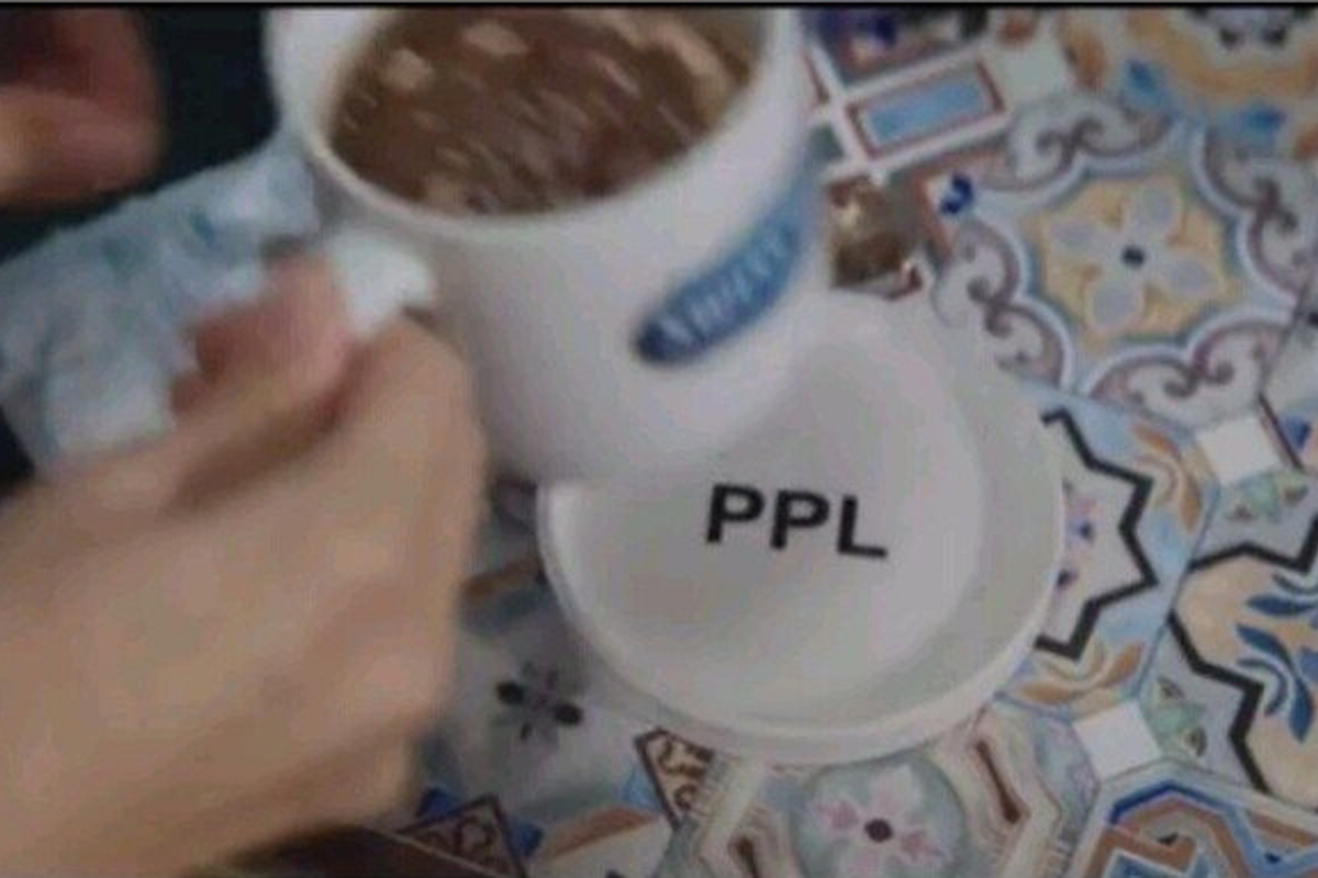 一個白色咖啡杯放在桌上，旁邊的杯墊上寫著PPL字樣。