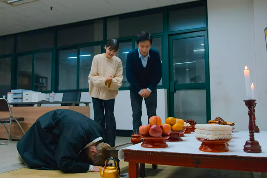 两人站在房间内，面对铺设在桌子上的传统仪式用品。