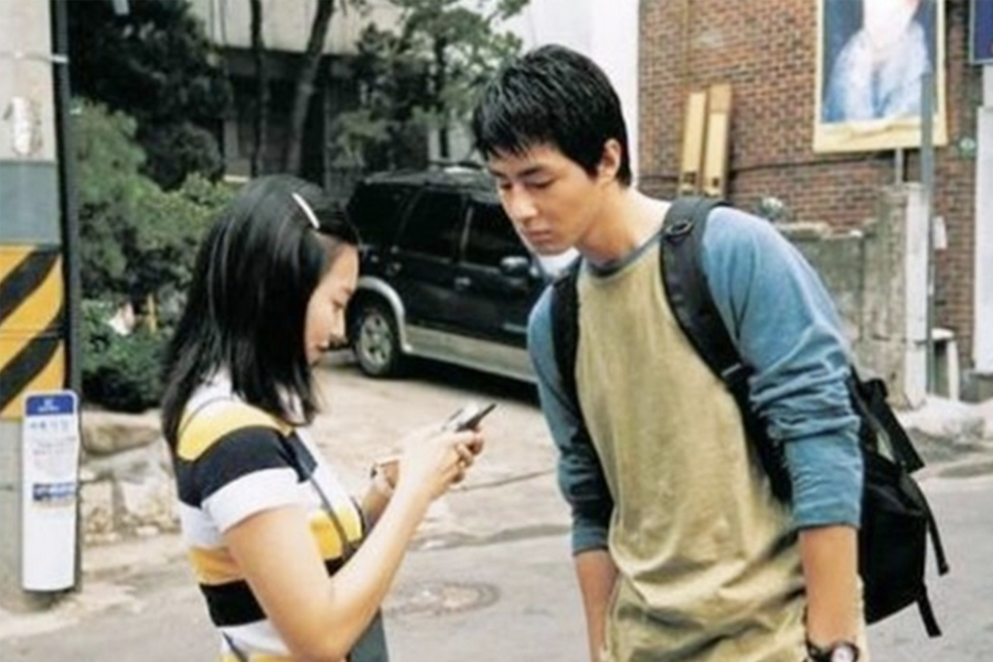 两人站在户外，一个人正看着另一个人的手机屏幕。