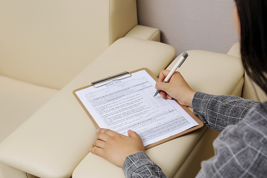 有人在沙发上填写问卷或表格，手里握着笔。
