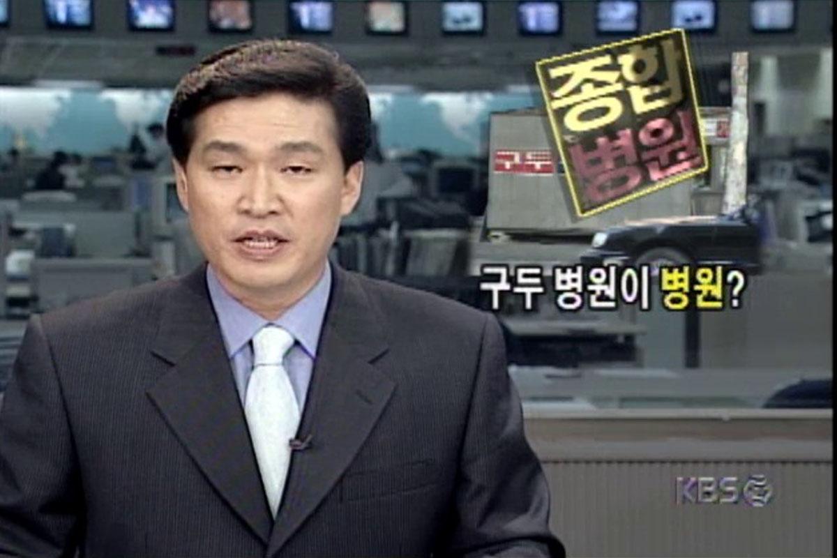 ชายคนหนึ่งอ่านข่าวในห้องส่ง โดยมีภาพคำบรรยายเป็นภาษาฮันกึลเกี่ยวกับโรงพยาบาลและสัญลักษณ์ของ KBS บนหน้าจอ