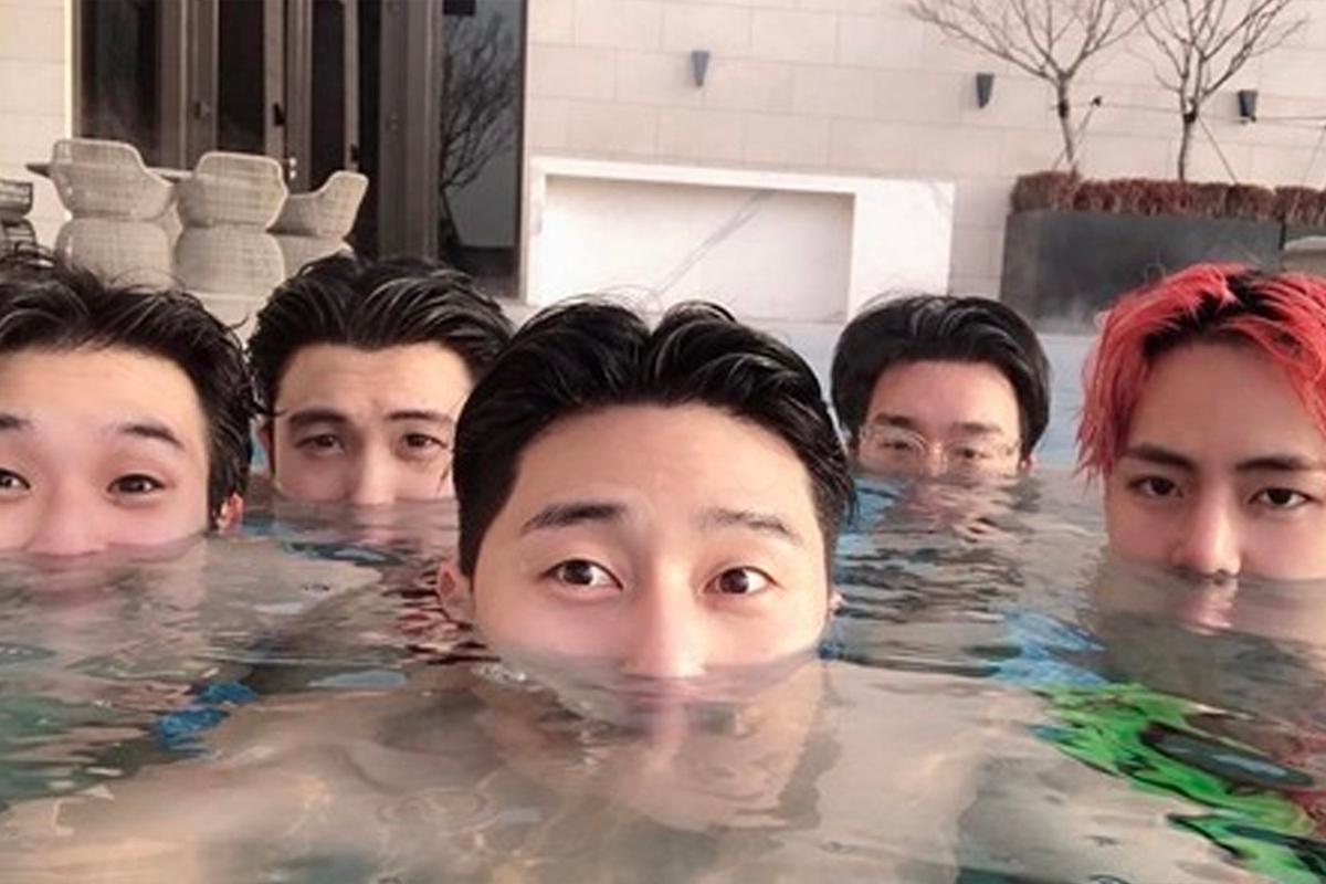 韓星好友在泳池裡,僅露出頭部,背景為現代風格建築,表現出休閒的時刻。