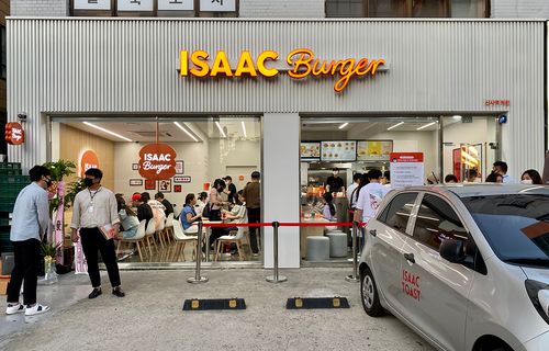 ISAAC Burger exterior with people inside and outside of the store seen through the glass windows
