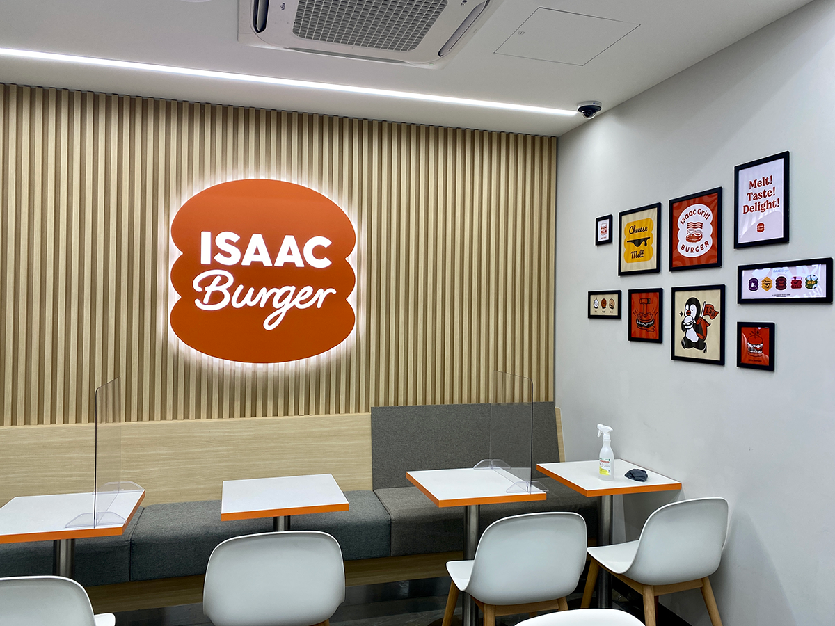 ISAAC Burger sign on wooden wall and white tables and chairs