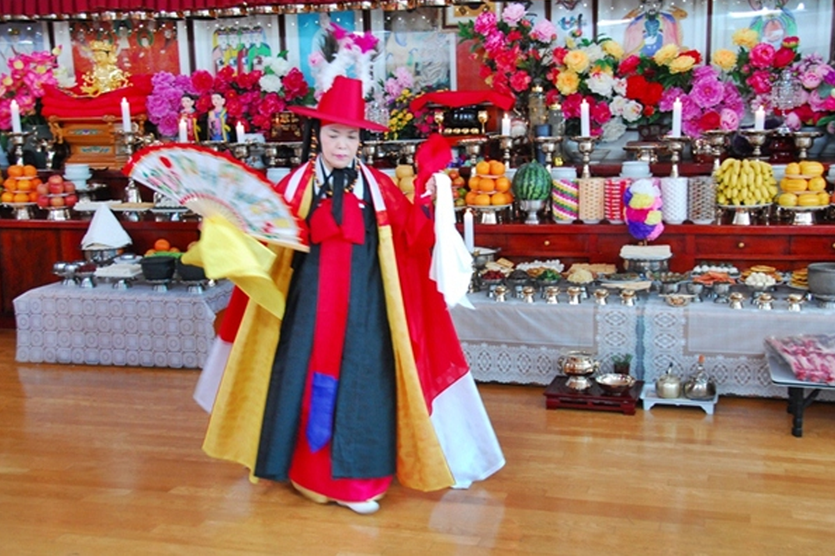 Korean shaman, mudang, performing a rite in colorful fabric