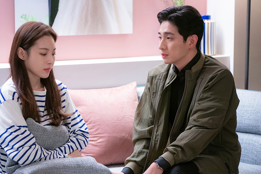 情侣坐在沙发上交谈，背景有婚纱画作，反映同居话题中的文化差异。