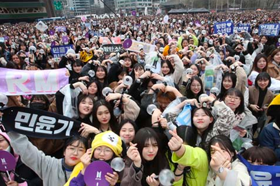 粉絲聚集於韓國偶像演唱會場地，手持應援物，展示對偶像的支持與熱愛。