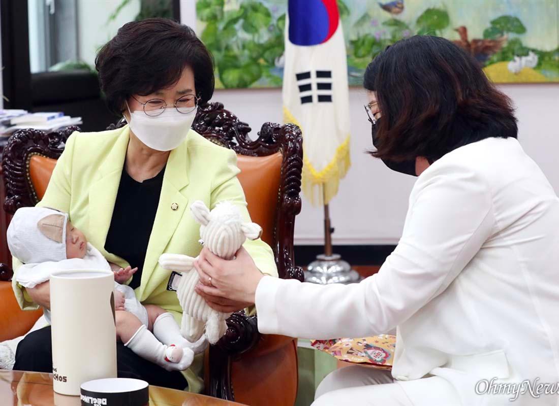 นักการเมืองหญิงเกาหลีรับของเล่นจากผู้หญิงอีกคนในขณะที่ลูกน้อยอยู่บนตักภาพนี้แสดงออกถึงความลงตัวระหว่างการทำงานและการเลี้ยงลูก