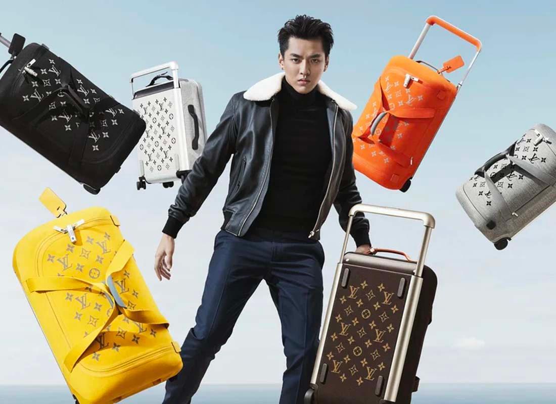 ดาราชายเดินผ่านกลุ่มแฟนคลับและสื่อมวลชนในชุดสูทสีเข้ม