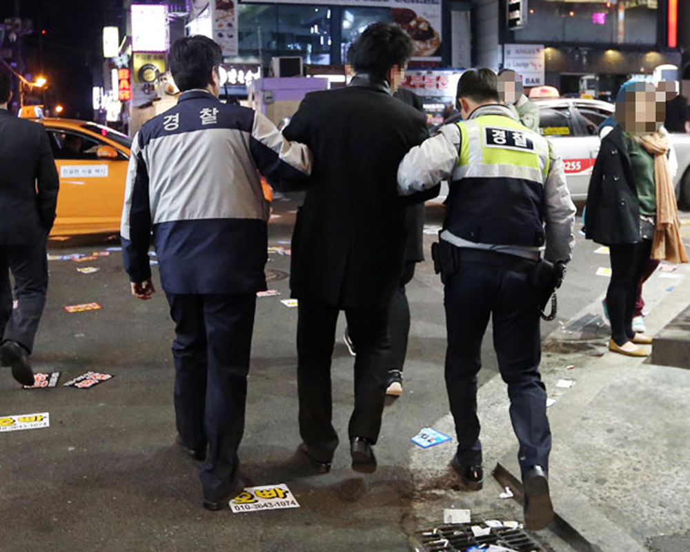 Korean police officers patrolling at night helping drunk person