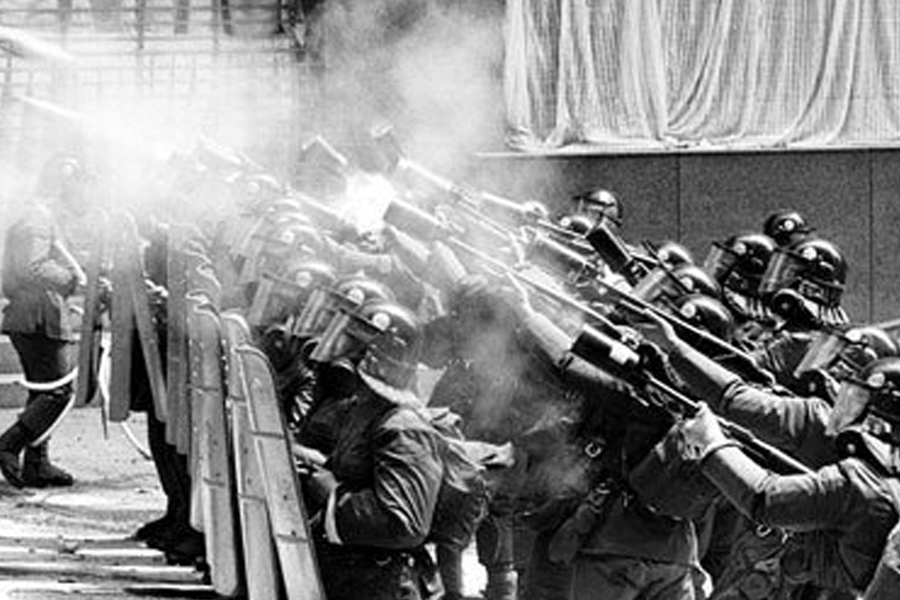 历史照片展示韩国警察在示威活动中使用防暴装备，烟雾弥漫，展现出当时动荡时期的紧张局势。