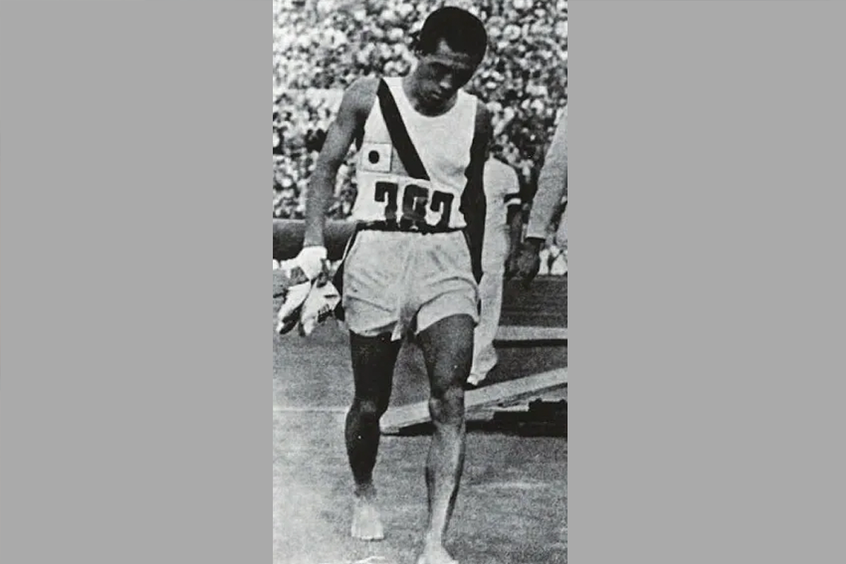 运动员比赛结束后，脱下跑鞋，走出赛场。