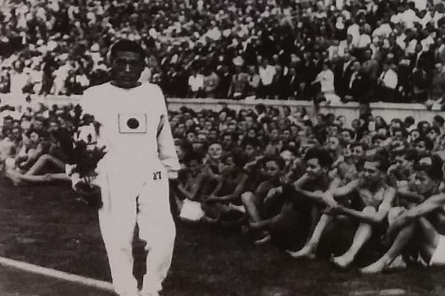 获得奖牌的运动员与同伴在领奖台上，背景是满场观众。