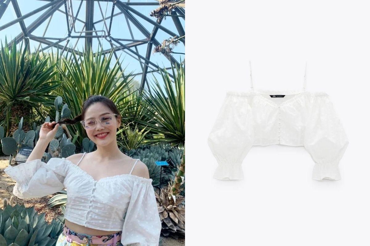緑の植物やサボテンに囲まれたガラスの温室内で、白いオフショルダーブラウスを着用し、ピンクのスカートを合わせたファッションコーディネート。韓国流行の白いフリルオフショルダーブラウスは爽やかで夏にぴったりのアイテム。