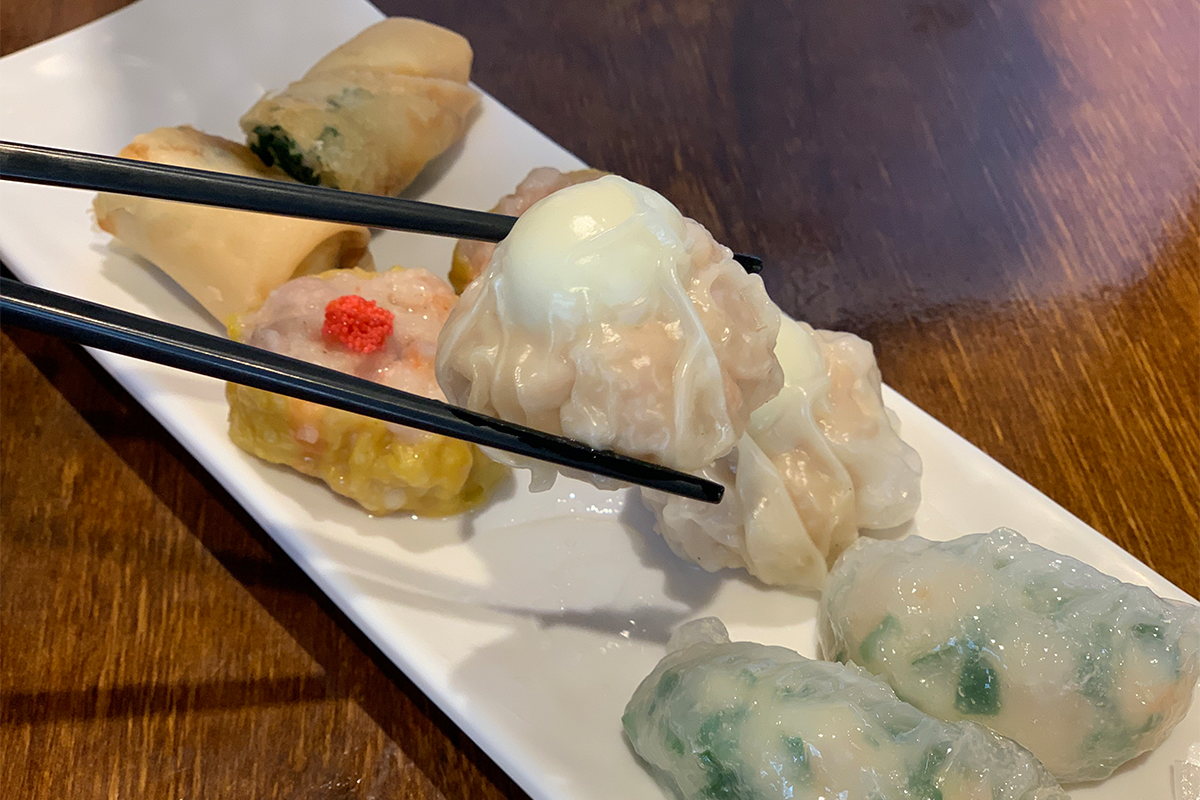 筷子夾著一顆扣軋燒賣，上面壓著一顆鵪鶉蛋，這道點心的獨特之處令人矚目。