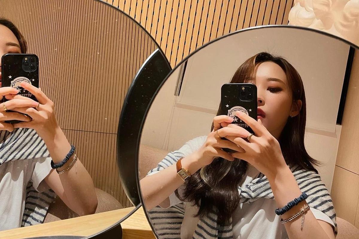手持手機的女子在鏡子前自拍，鏡子顯示她的臉部和手機。