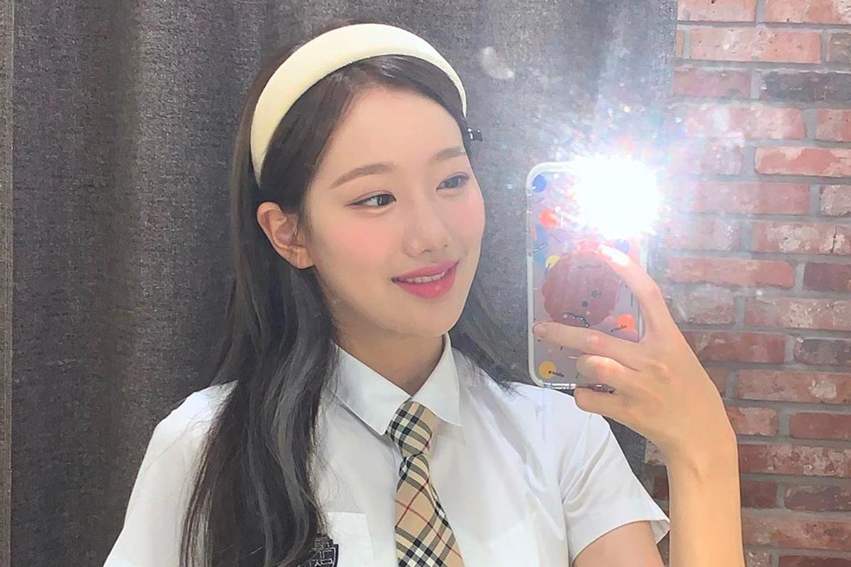 豎起耳朵的女子在鏡子前用手機自拍，穿著學校制服，臉龐被手機和閃光燈反射。