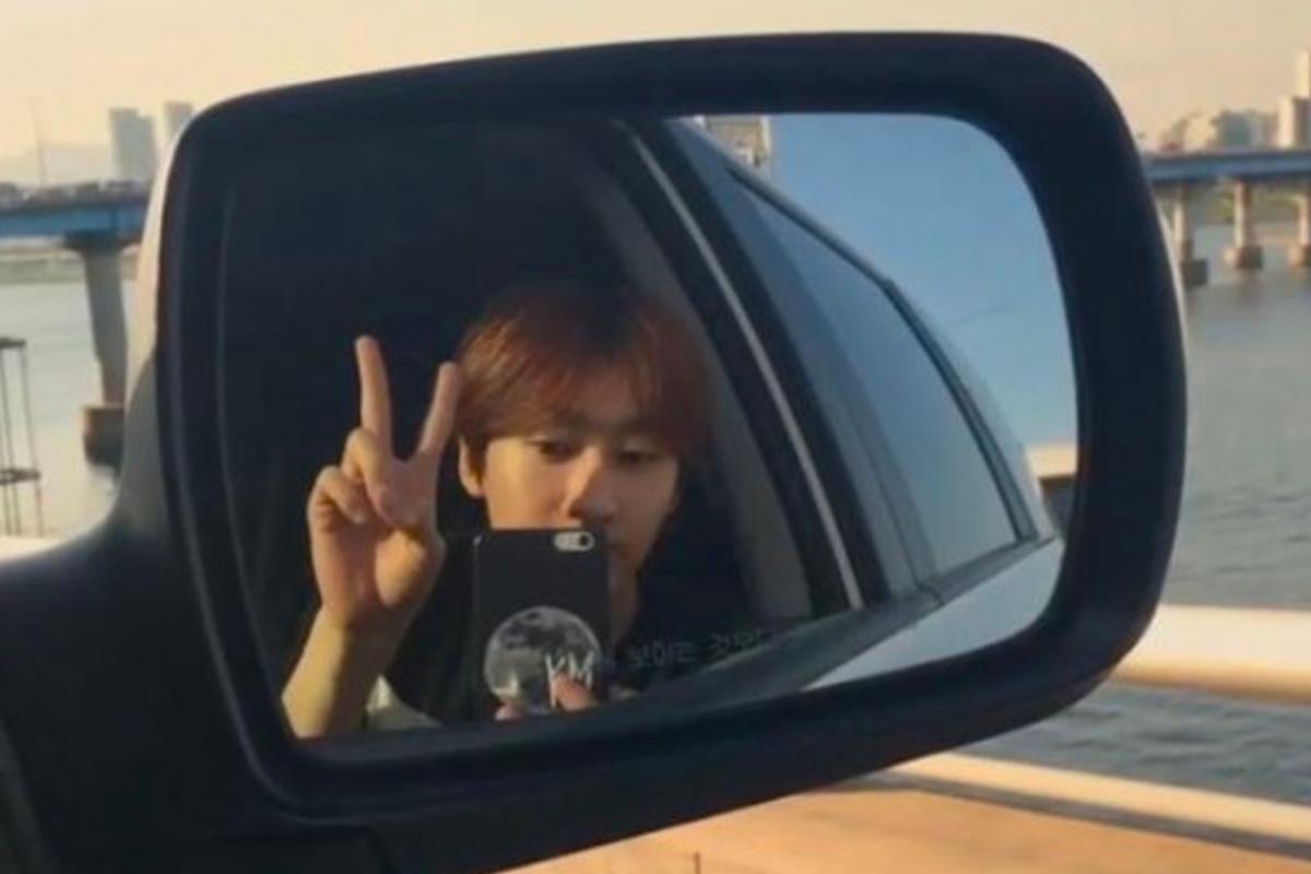 從車內看出去的車側倒後鏡自拍，背景中有橋樑和水景，停靠在橋上能看到城市景色。