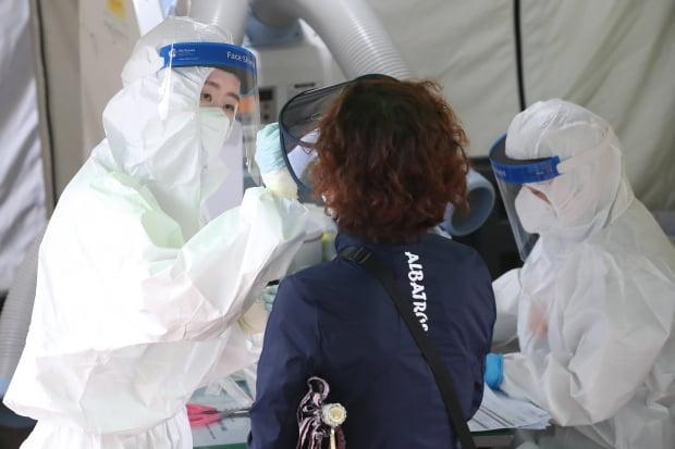 大邱・達城区の保健所で、防護服を着た医療スタッフが市民から新型コロナウイルス検査のサンプルを採取しています。