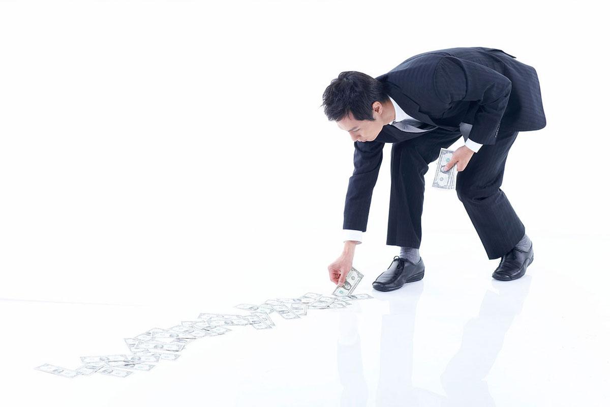 man in a suit picking up money on the white floor