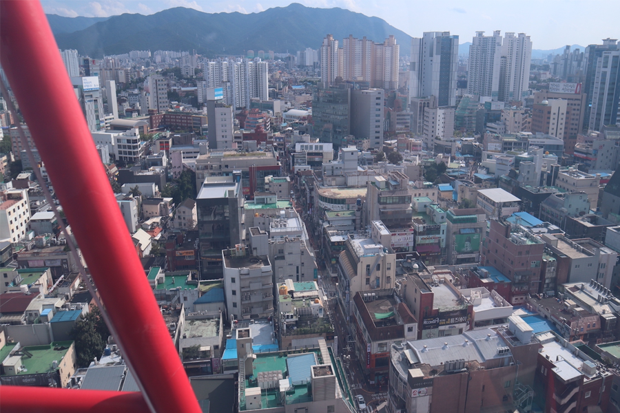 从室内游乐场的窗户俯瞰大邱的城市景观,展现繁忙的都市生活与高楼大厦的排列。