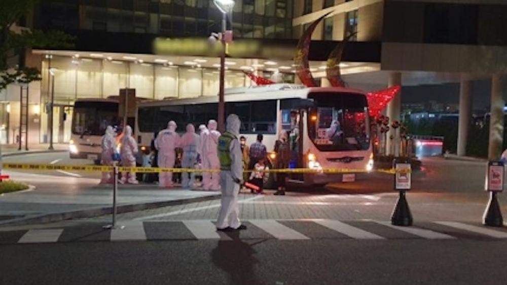 Afghan refugees arriving at a hotel in Gimpo, greeted by staff in protective gear and police escort.