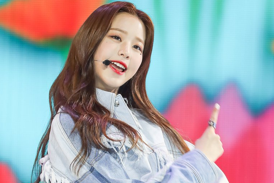 IZ*ONE 成员在舞台上表演，穿着牛仔外套，背景色彩缤纷