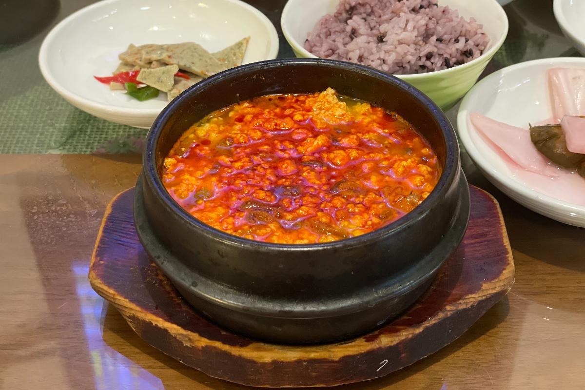 Schüssel mit scharfem weichem Tofueintopf und Beilagen auf einem Tisch im Osegyehyang Restaurant