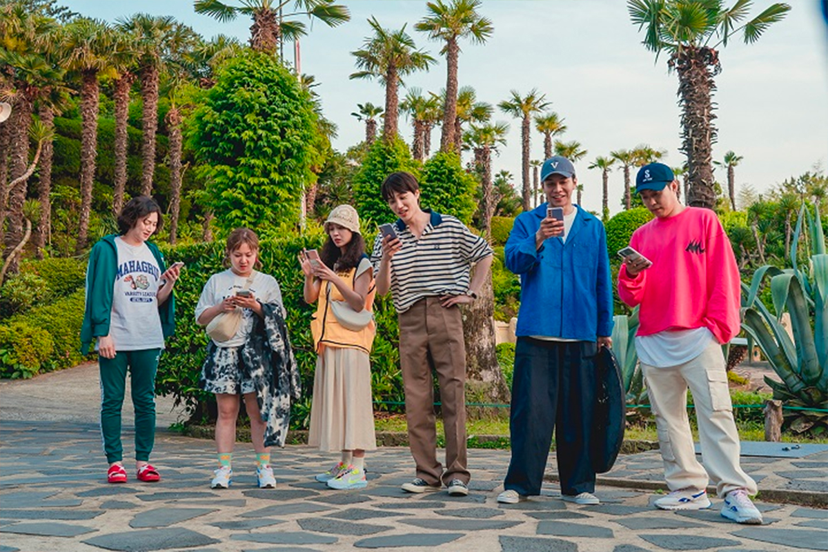 Các thành viên của chương trình New World đang đứng trên đảo Oedo, phía sau là những cây cọ và thực vật xanh tươi ở vườn sinh thái Oedo-Botania, Geoje, Hàn Quốc.