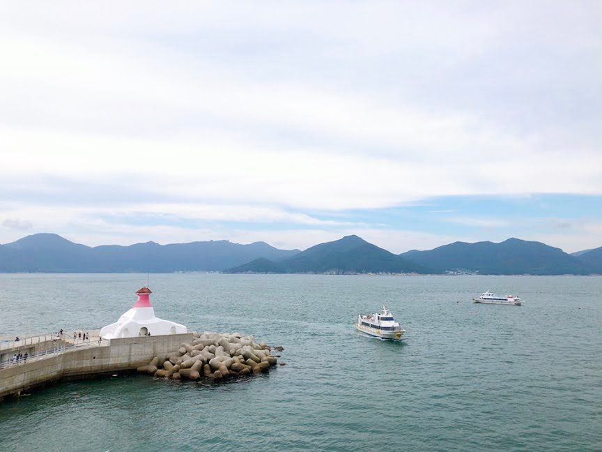 Khung cảnh bến tàu với ngọn hải đăng màu trắng và đỏ nhìn ra biển ở đảo Oedo, Geoje, Hàn Quốc.