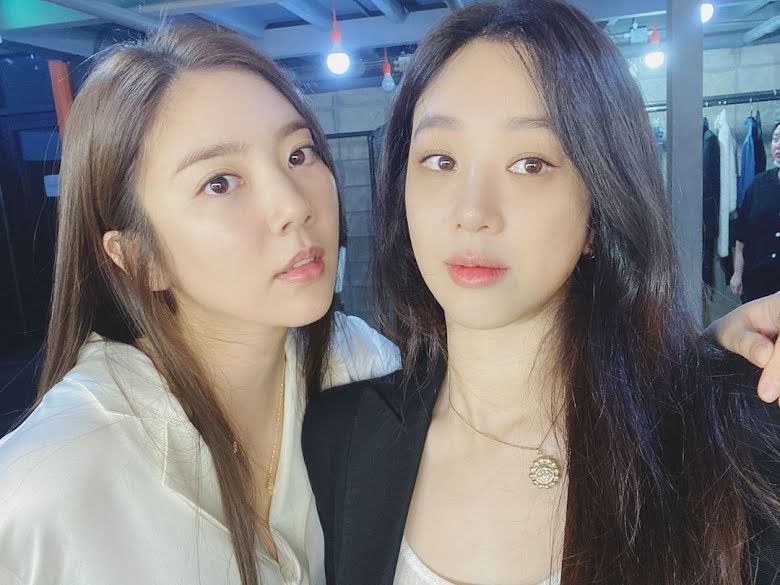 Schauspielerin Son Dambi lächelt und posiert für ein Foto in einem stilvollen Outfit mit Kettenanhänger.