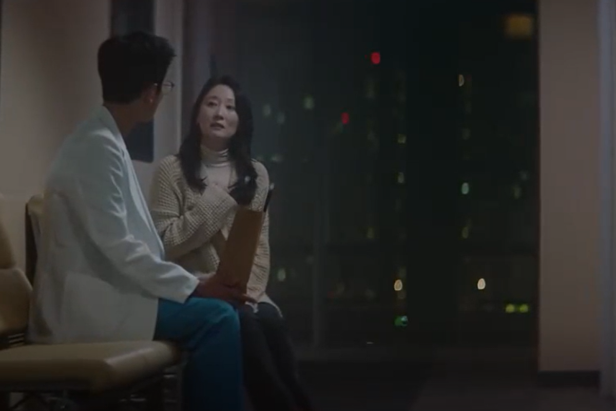 Cảnh phim Hospital Playlist cho thấy người phụ nữ đang nói chuyện với một bác sĩ trong bệnh viện vào ban đêm.