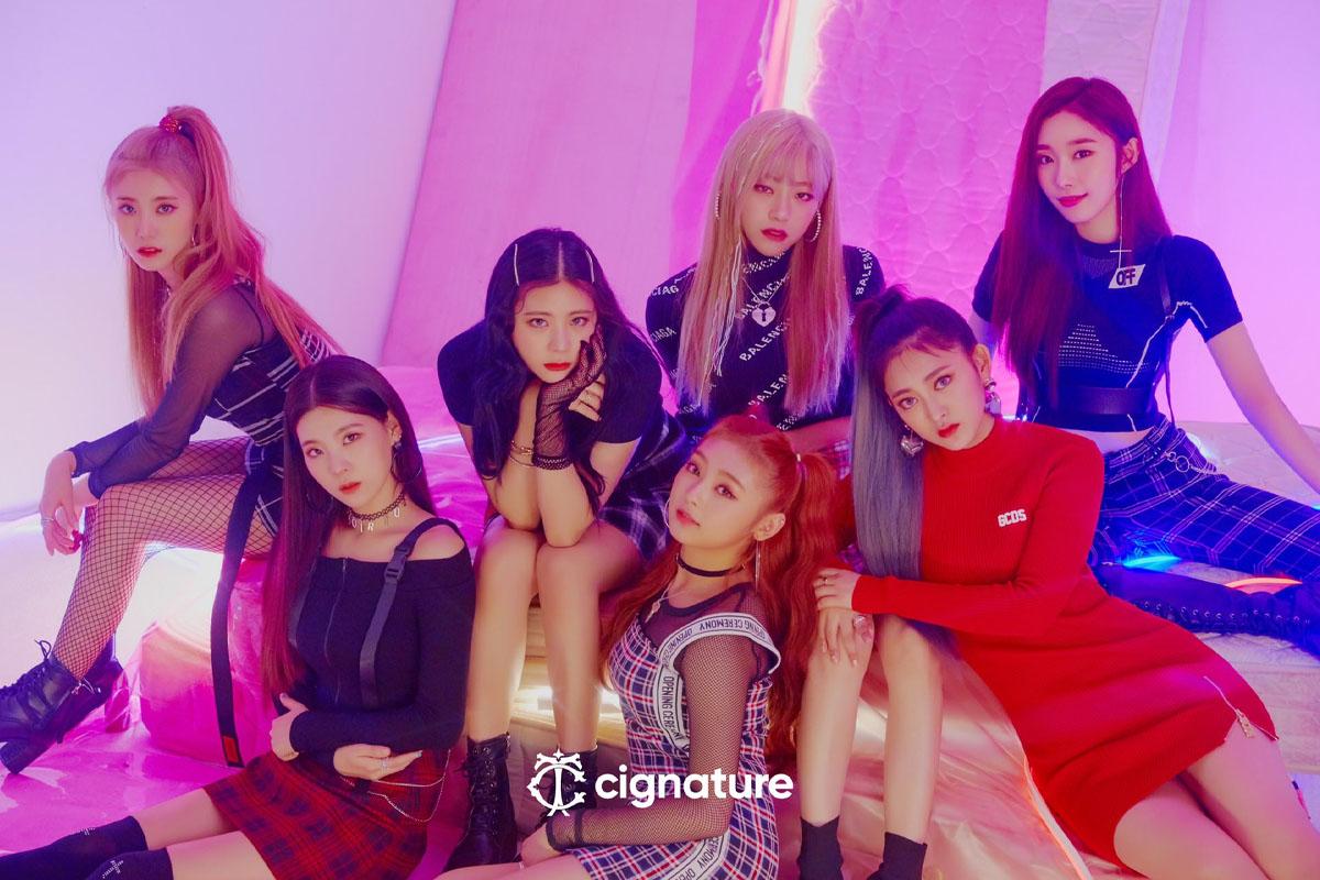 韓國女團 Cignature 成員以七位成員組成，坐在牀上，展現出時尚風格的服裝和造型。
