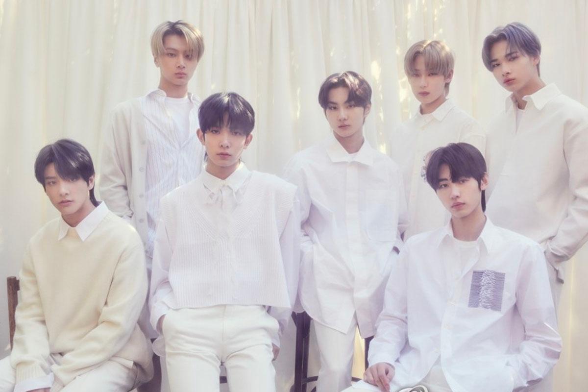 สมาชิกวง ENHYPEN สวมชุดสีขาวนั่งร่วมกัน ถ่ายภาพภายในสตูดิโอที่มีผ้าม่านสีขาวเป็นฉากหลัง