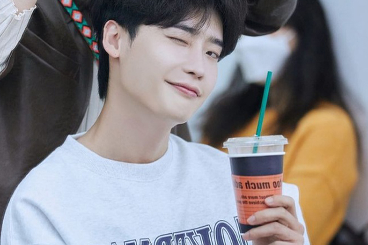 韓國人氣男演員手持飲品的側面肖像，面部模糊不清，配上休閒衞衣造型，背景模糊