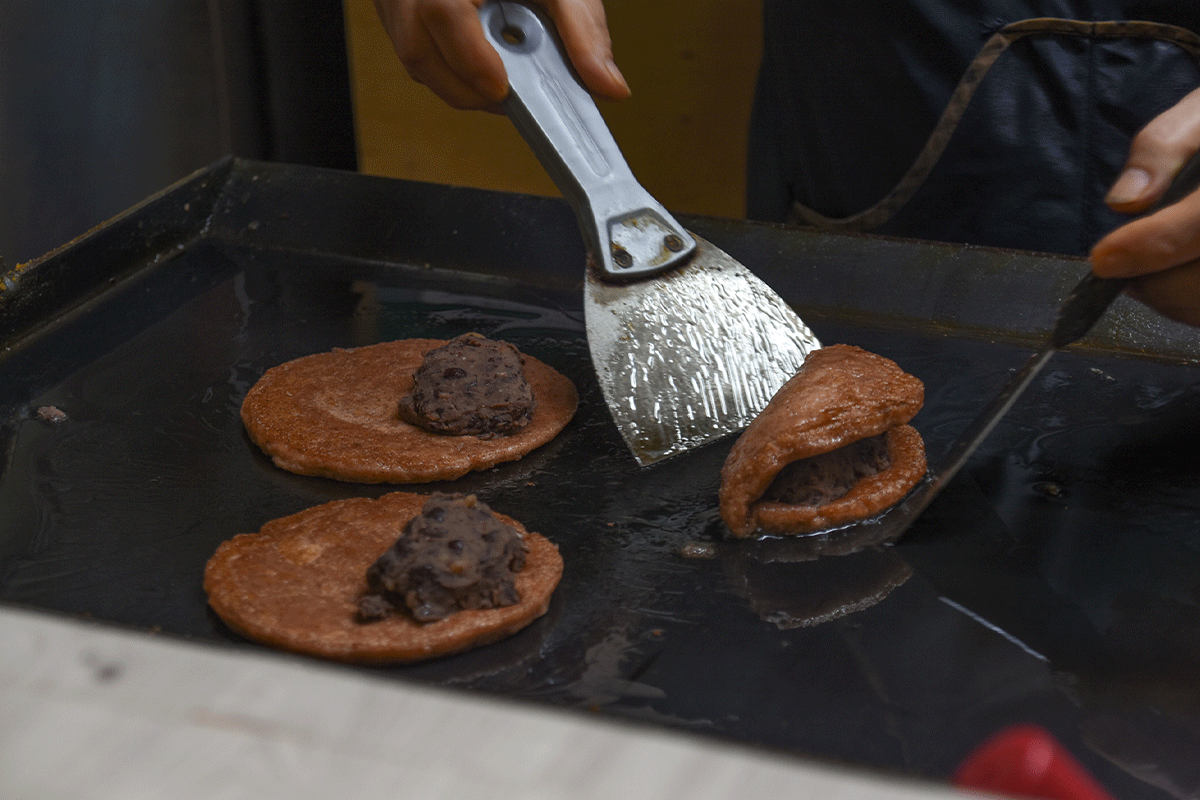 Một chiếc bánh gạo rán Hàn Quốc (Bukkumi) trên chảo nóng, được nhồi với đậu đỏ nghiền kĩ, đang được chế biến tại các chợ tại Samcheok.