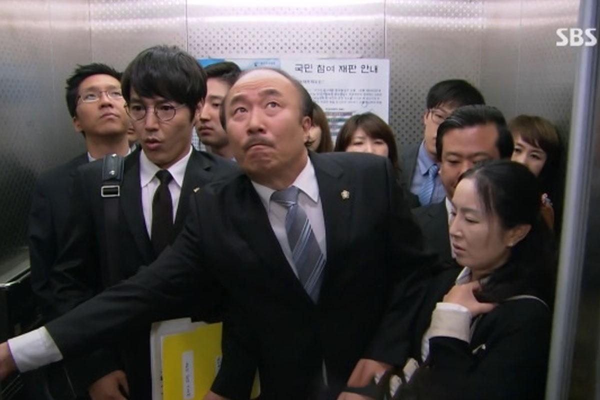 ชายคนหนึ่งในชุดสูทกดปุ่มปิดประตูลิฟต์ พฤติกรรมแสดงความใจร้อนของคนเกาหลีในลิฟต์