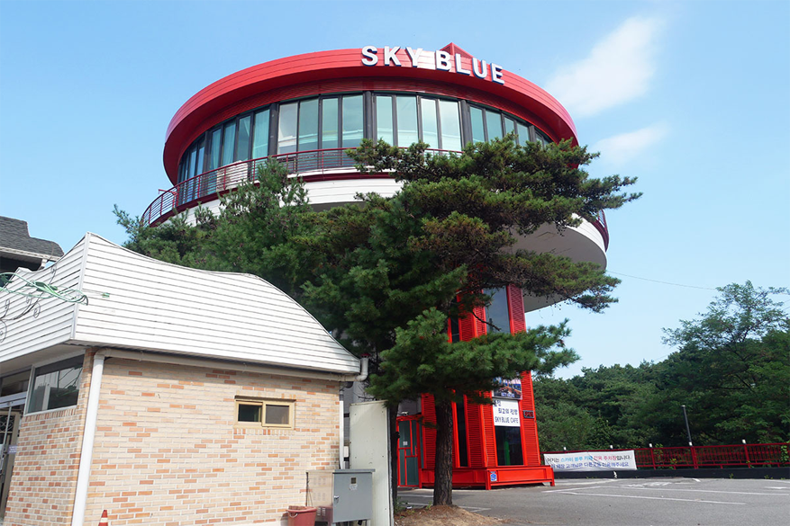 九峰山SKY BLUE咖啡廳的近景展示,圓頂的咖啡廳設計前襯著藍色天空,並有樹木環繞