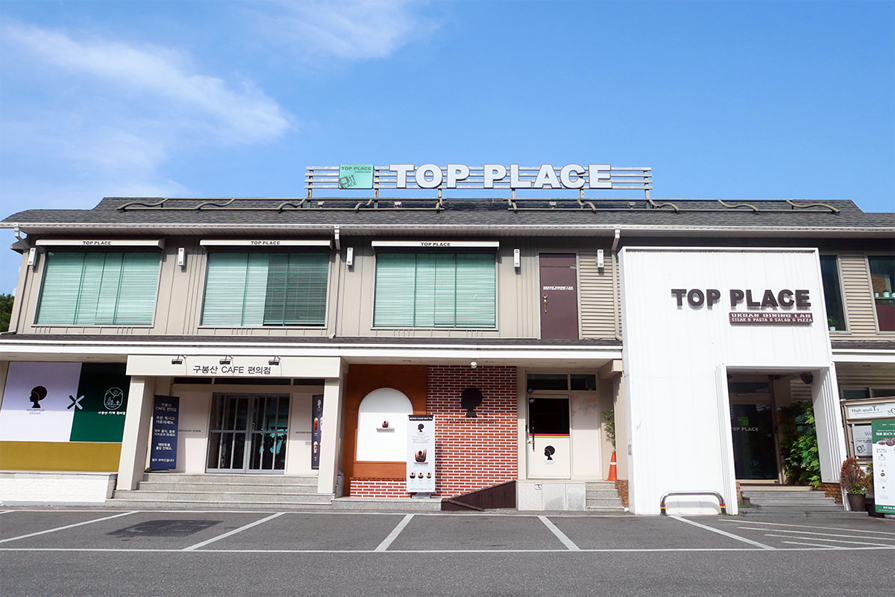 TOP PLACE咖啡廳的外觀,有著方正的建築設計,正面有大型窗戶和簡約的招牌,適合聚會的地點之一