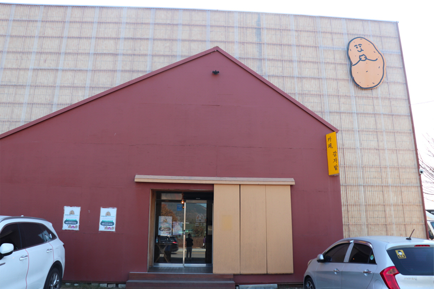 位于春川的马铃薯田咖啡厅外观，墙上有可爱的马铃薯娃娃标志，体现了乡村风情。