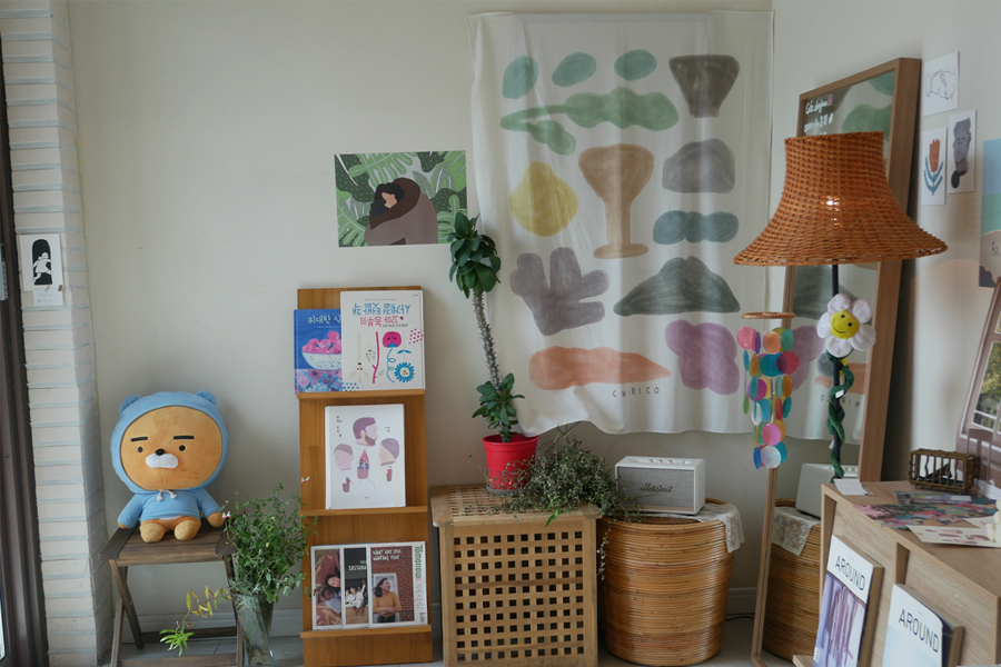 一個咖啡廳的角落裝飾，包含書籍、植物和布偶。