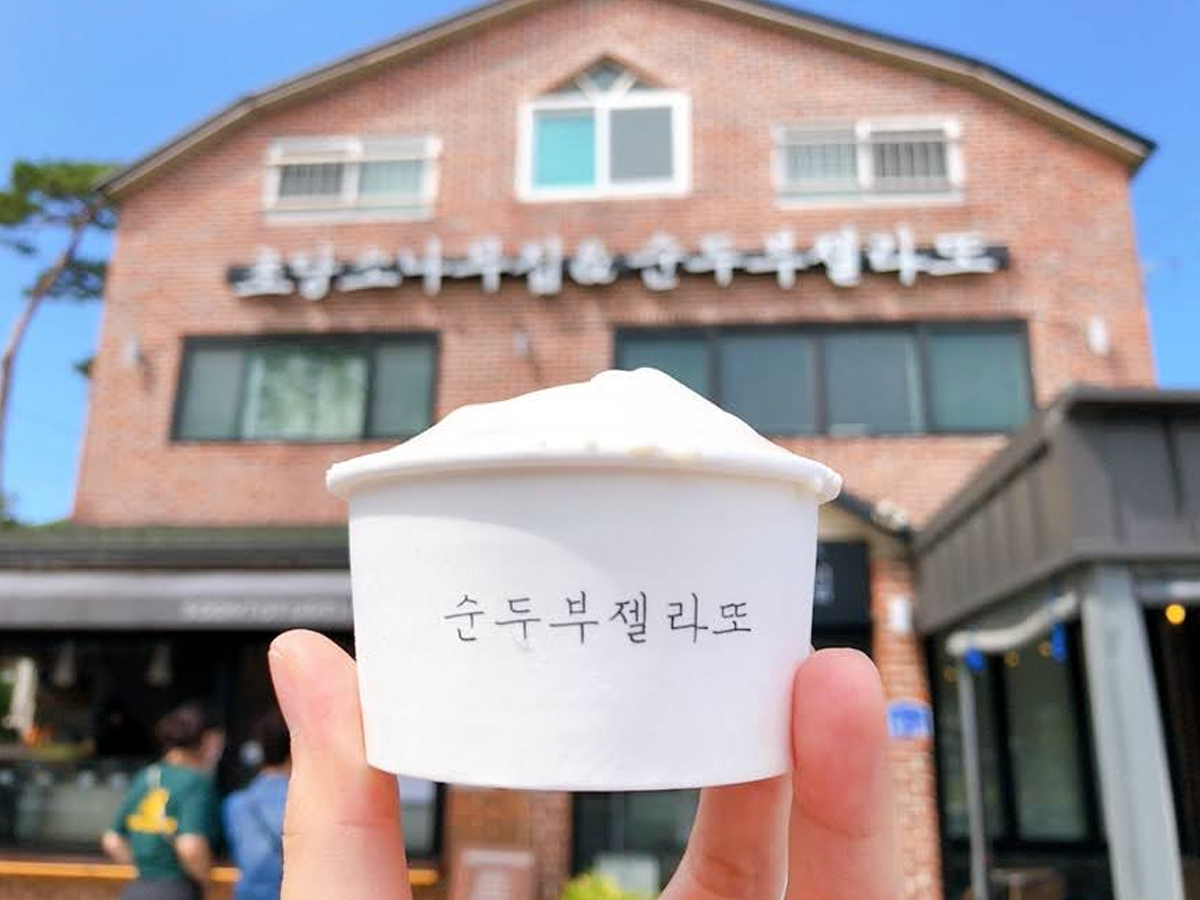 手持一杯豆腐冰淇淋，背景是冰淇淋店外觀。