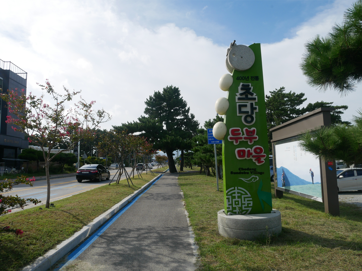 韓國江陵市，顯示朝鮮村的標誌和路邊樹木的圖片。