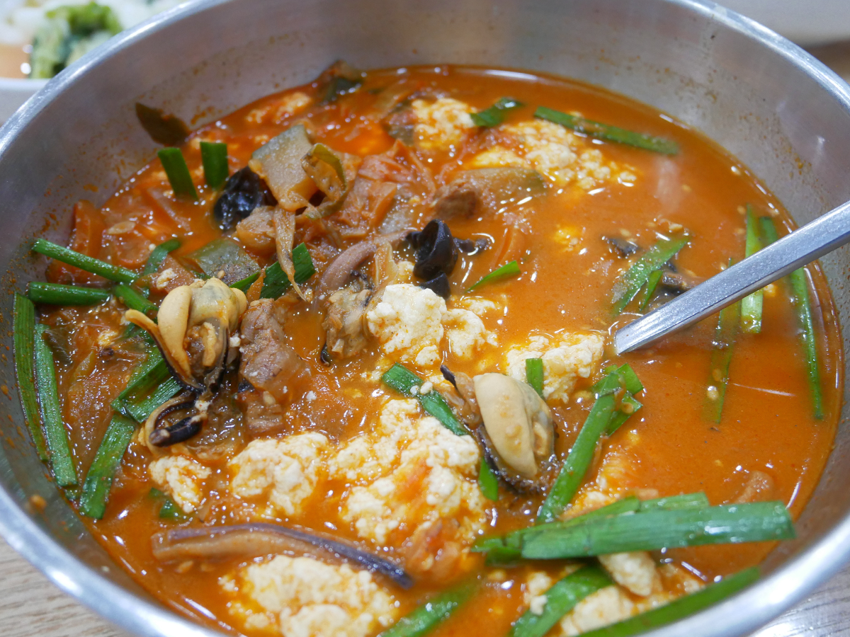 近拍海鮮嫩豆腐湯，顯示海鮮和蔬菜與嫩豆腐混合。