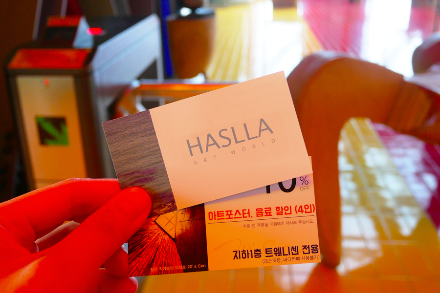 哈斯拉藝術村的入場票券，背景為藝術村內部一角。