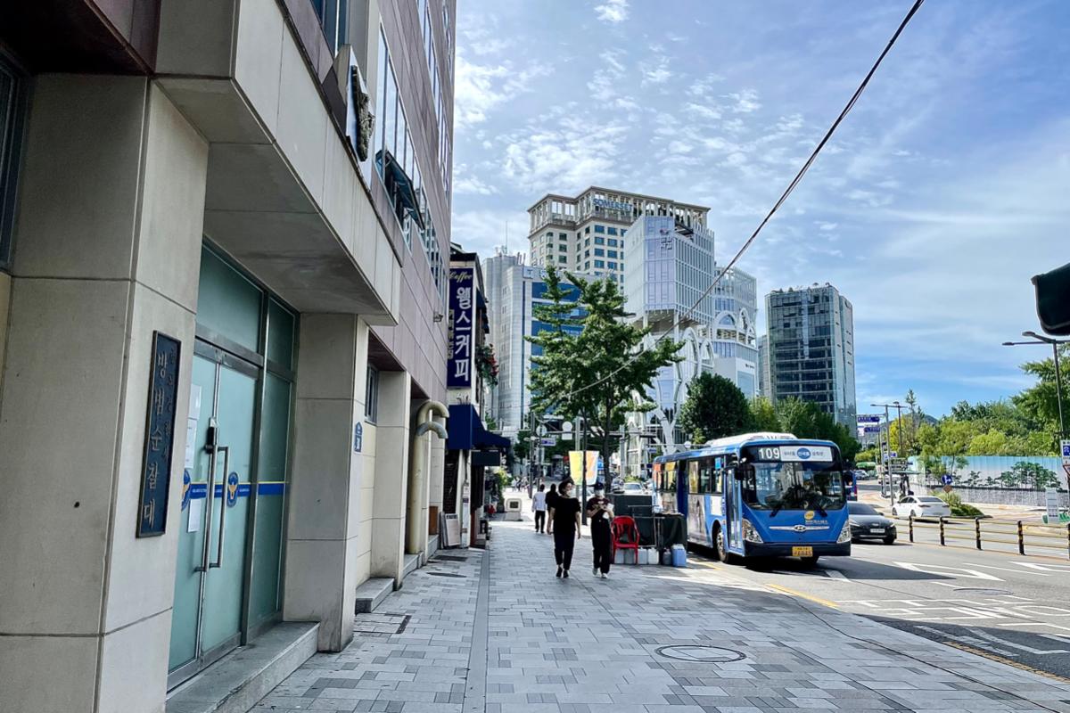 Rue moderne à Séoul avec des édifices élevés et un autobus passant, représentant l'environnement urbain autour d'Insadong.