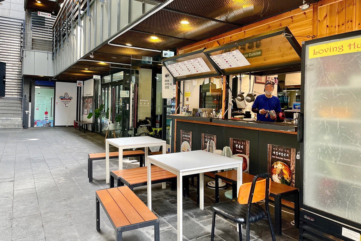 Snack-bar vegan à Insadong, Séoul, avec des tables extérieures disponibles pour les visiteurs, situé dans une allée pavée et charmante.