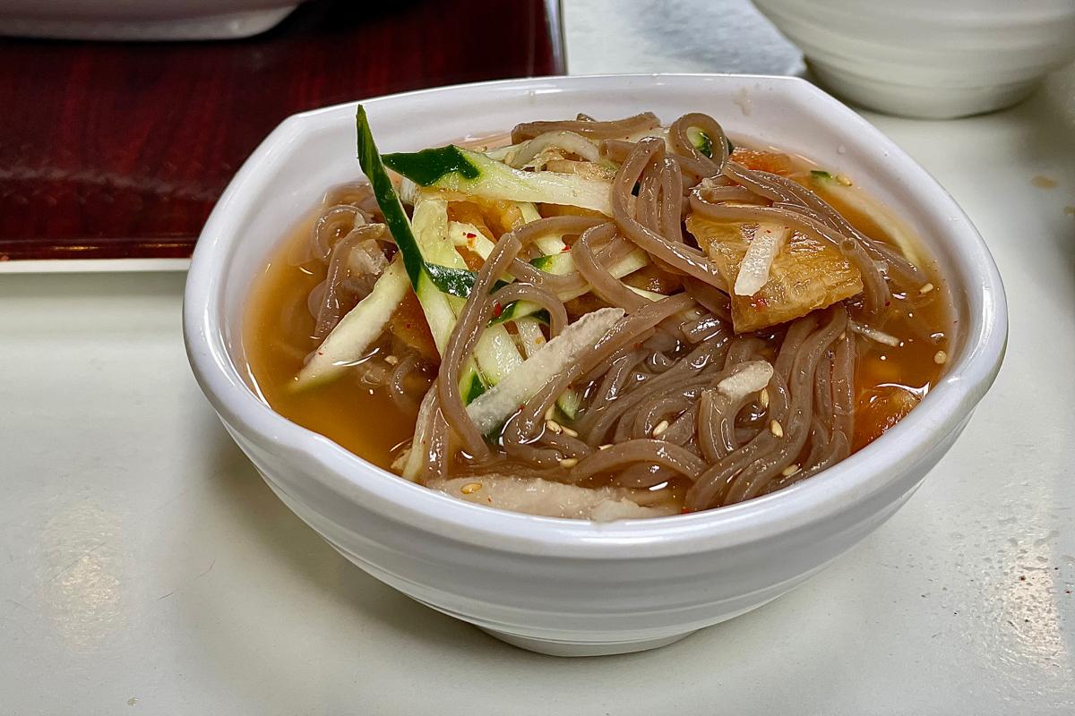 Petit bol de nouilles de sarrasin froides dans l'eau de radis, montrant une portion de plat végan traditionnel coréen, à Insadong, Séoul.