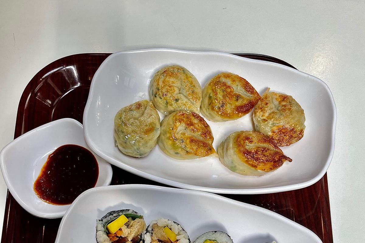 Raviolis frits servis au snack-bar Maru JaYeonSik Kimbap végan à Insadong, accompagnés de sauce piquante dans une assiette blanche.