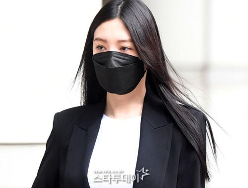 AFTERSCHOOLの元メンバー、パク・スヨンの裁判出席時の姿。白いトップスに黒いジャケットを着用し、ロングヘアが風に揺れている